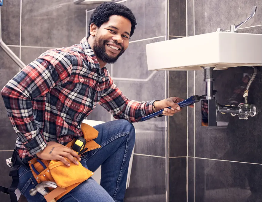 Man repairing sink in plaid shirt