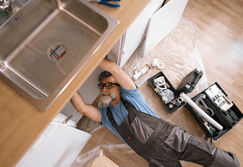 Technician working beneath kitchen counter